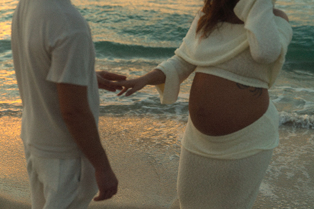 Photo of man and woman holding hands on the shore of the beach