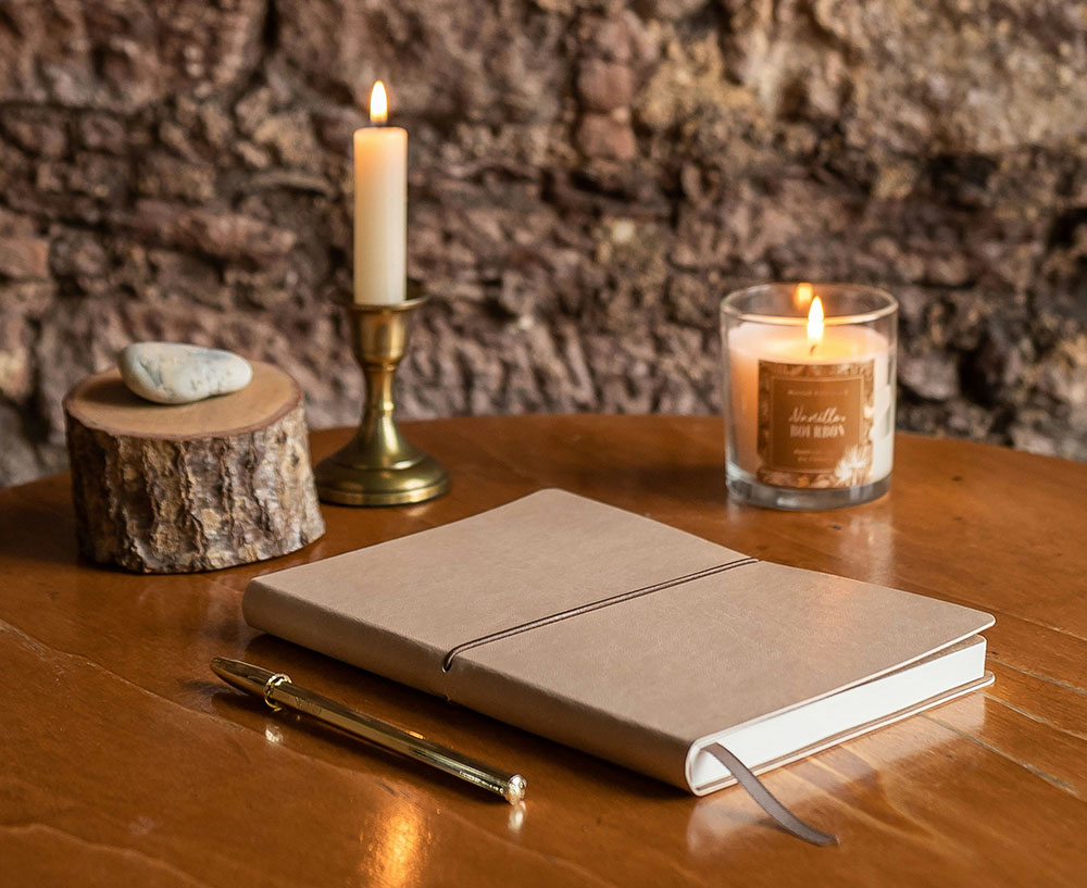 Photo of journal on a table accompanied by a candle and other decor