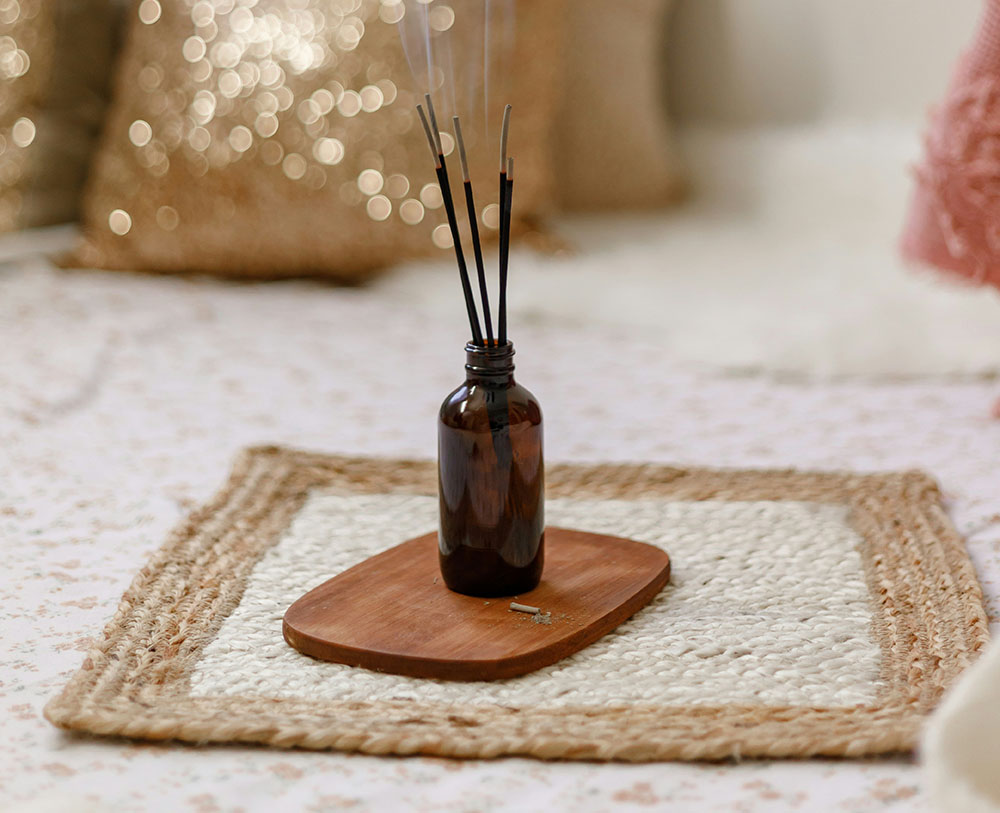 Photo of brown glass bottle holding incense sticks that are burning